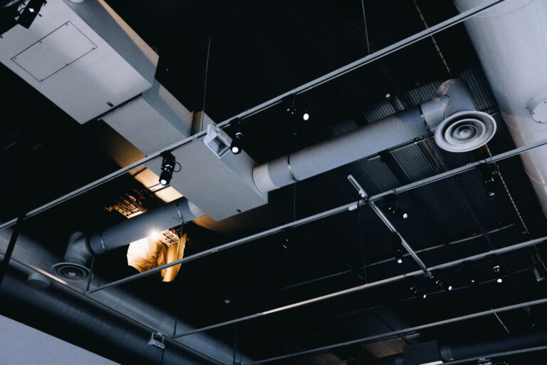 low-angle-shot-metal-black-ceiling-with-white-ventilation-pipes